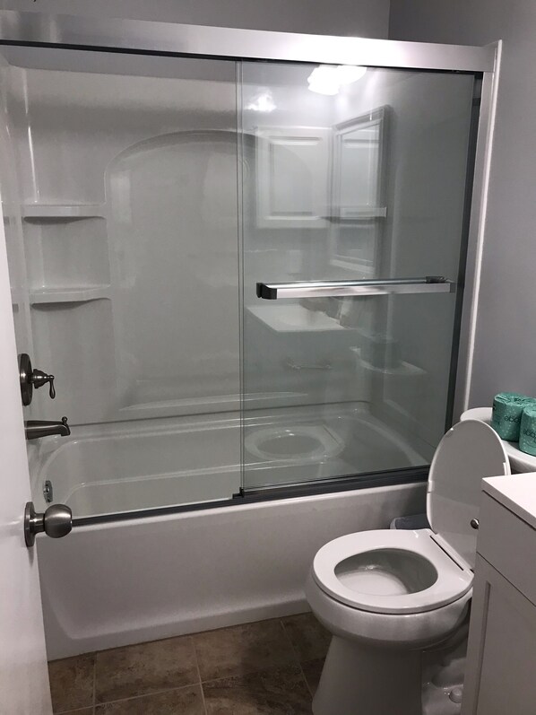 Une salle de bain moderne avec une douche à parois de verre, des toilettes blanches et un lavabo avec un plan de travail.
