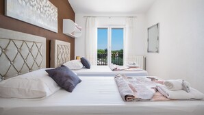 A hotel room with two beds, a view of the outdoors, and a large painting on the wall.