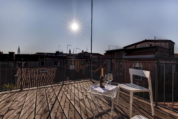 Una terraza en la azotea con una mesa para dos, una botella de champán y una copa.