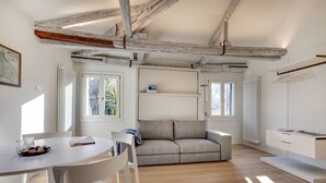 A modern living room with a sofa, a dining table, and a white cabinet. - VENICE SKYLINE VIEW STUDIO APARTMENT M0270429079 (Venice)