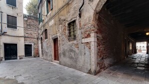 A narrow alleyway with old buildings, a brick wall, and a wooden door. - VENICE SKYLINE VIEW STUDIO APARTMENT M0270429079 (Venice)