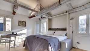 A bedroom with a bed, a desk, and a chair. - VENICE SKYLINE VIEW STUDIO APARTMENT M0270429079 (Venice)