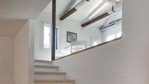 A staircase with white walls and wooden beams. - VENICE SKYLINE VIEW STUDIO APARTMENT M0270429079 (Venice)