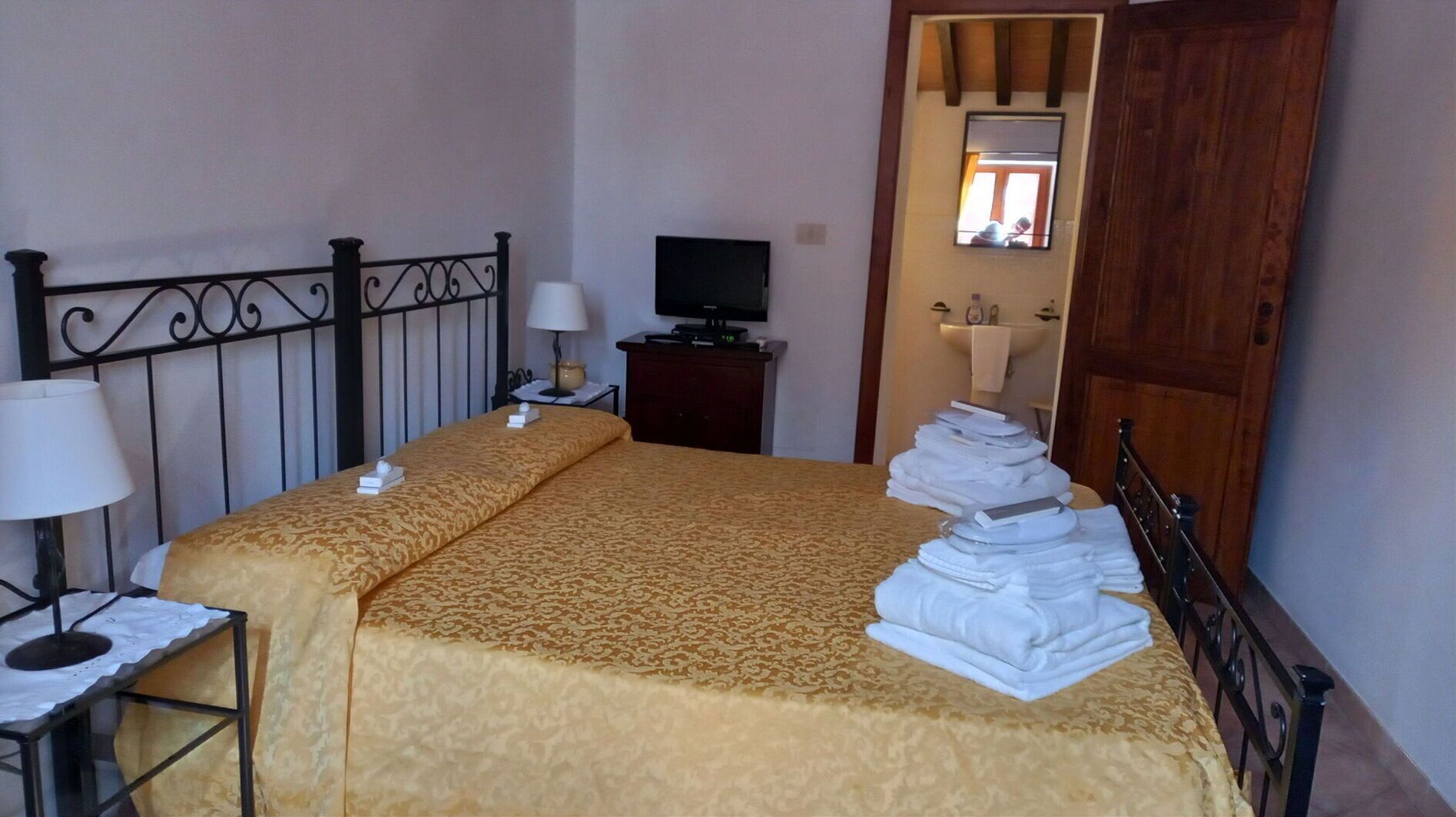 Een hotelkamer met een bed, een televisie, een nachtkastje en een badkamer zichtbaar door een geopende deur.