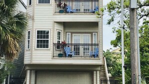 A two-story house with a garage, a balcony on the second floor, and a utility pole with a sign. - Boardwalk Home One Block to Kemah Activities  (kemah)