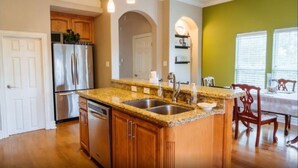 A kitchen with granite countertops, stainless steel appliances, wooden cabinets, and a dining area with a table and chairs. - Boardwalk Home One Block to Kemah Activities  (kemah)
