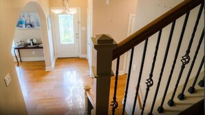 A staircase with a wooden handrail and black balusters, leading to a room with a wooden floor and a door with a frosted glass window. - Boardwalk Home One Block to Kemah Activities  (kemah)