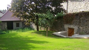 A stone building with a small garden area, a tree, and a concrete structure. - DETACHED APARTMENT IN ANNECY'S HISTORICAL CENTER WITH PRIVATE GARDEN (Annecy)