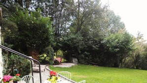 A patio with a table and chairs, surrounded by a garden with trees and a gravel path. - DETACHED APARTMENT IN ANNECY'S HISTORICAL CENTER WITH PRIVATE GARDEN (Annecy)