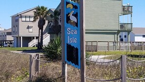 Señal de Sea Isle con una ilustración de una gaviota, rodeada de edificios residenciales y una zona cercada.