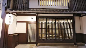 A traditional Japanese building with a wooden exterior, a sliding door with vertical slats, and a small sign above the door.