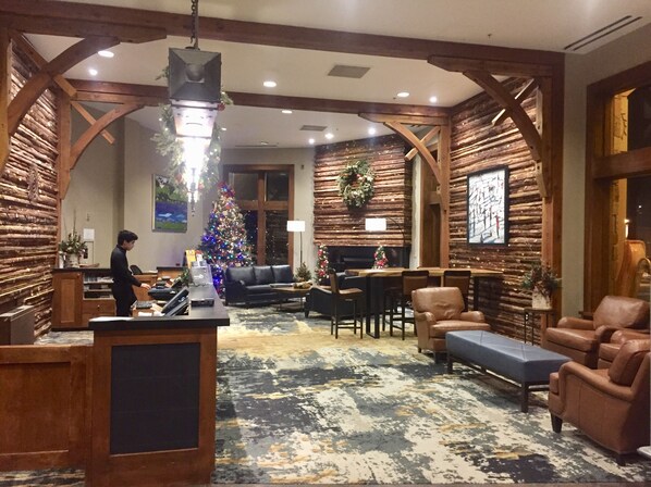 Un vestíbulo con detalles de madera, un árbol de Navidad, asientos de cuero y una recepción.