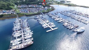 Ein Yachthafen mit zahlreichen vor Anker liegenden Booten, umgeben von einer kleinen Stadt und Hügeln im Hintergrund.