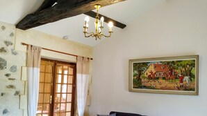 Un salon avec un canapé bleu foncé, une table en bois, un lustre, un tableau et un mur en pierre.