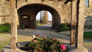 Une construction en pierre, dotée d’un toit en tuiles et d’une arche menant à un bâtiment.