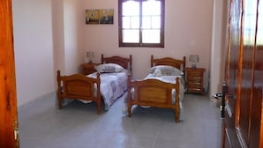 Une chambre à coucher avec deux lits en bois, une fenêtre et un tableau accroché au mur.