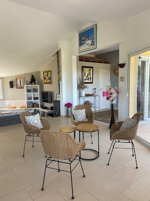 A spacious living room with wicker furniture, a television, and artwork on the walls. - House / Villa - SAINTE LUCIE DE PORTO VECCHIO (Zonza)