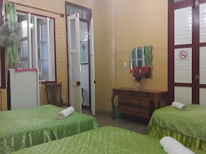 A hotel room with two beds, a wooden dresser, a mirror, and a fan. - Casa El Mirador - Yliana (Baracoa)