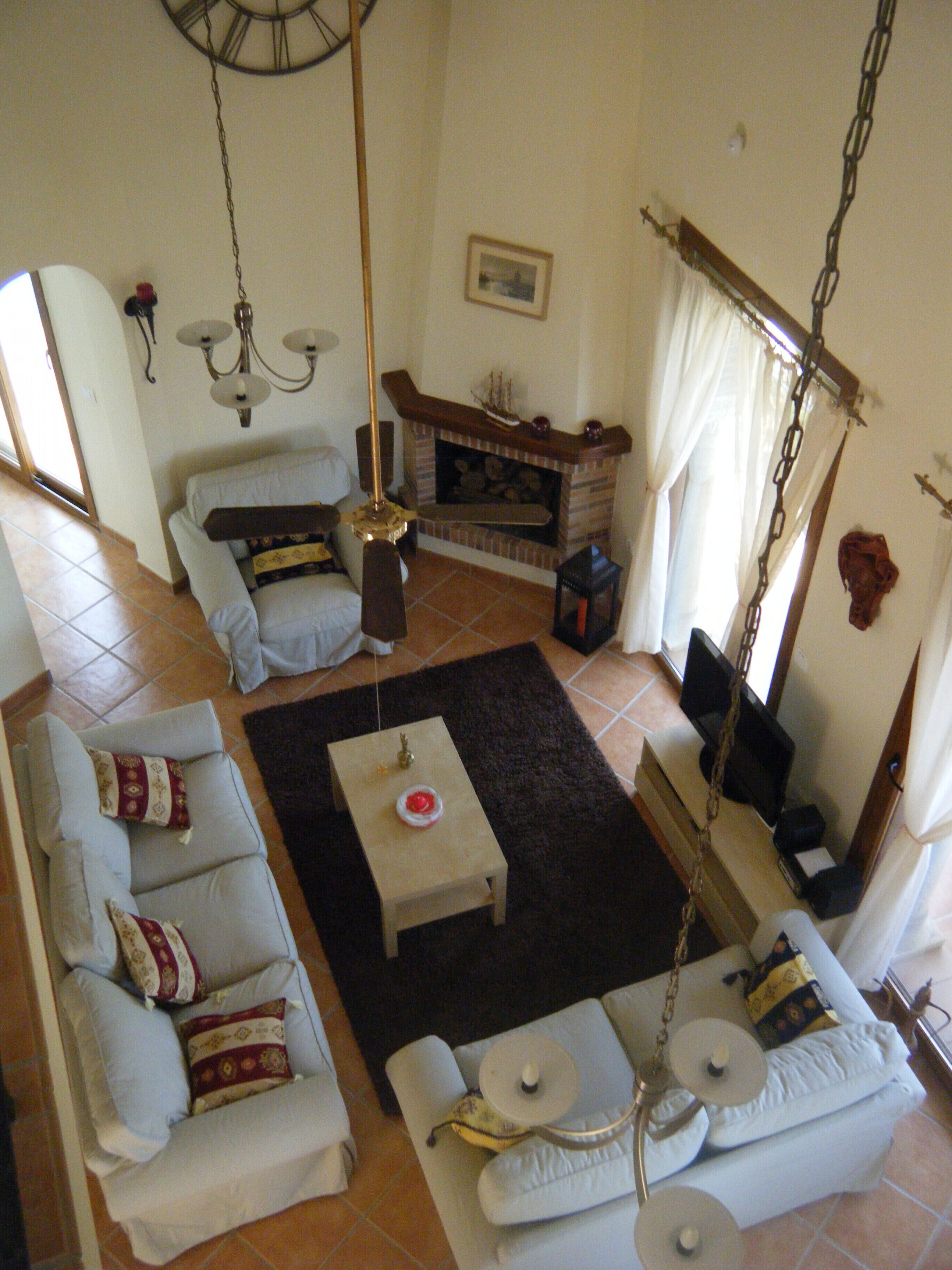 A living room with a fireplace, a sofa set, a coffee table, and a hanging light fixture.