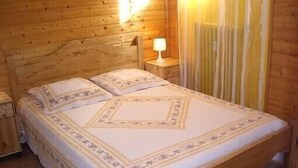 A wooden cabin-style room with a bed, nightstands, and a lamp. - T2 apartment in FONT ROMEU. Label 2 Clévacances. Exceptional panorama (Font-Romeu-Odeillo-Via)