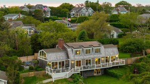 A large, multi-story house with a prominent balcony and a well-maintained garden.