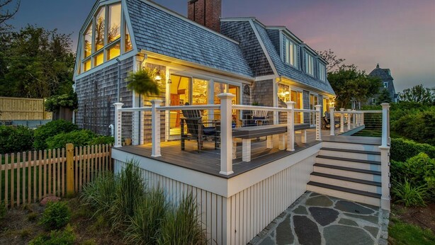 A two-story house with a covered porch and a stone staircase leading to the entrance.