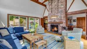 A spacious living room with a large fireplace, blue sofas, and a wooden coffee table.
