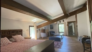 Un dormitorio amplio con una cama grande, un banco y techo de madera.