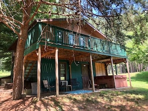 A rustic cabin with a green exterior, a covered porch, and a small outdoor seating area. - Secluded Getaway in Nature, close to Hocking Hills (Hocking Hills)