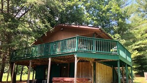 Een chalet met een overdekte veranda, een hottub en een houten terras.