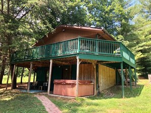 Une cabane dotée d’un porche couvert, d’un jacuzzi et d’une terrasse en bois.
