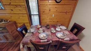 A dining table set with plates, cups, and cutlery, surrounded by wooden chairs in a room with wooden walls and a window with blinds. - Secluded Getaway in Nature, close to Hocking Hills (Hocking Hills)
