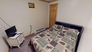 Une chambre à coucher comprenant un lit, une commode, un téléviseur et un radiateur.