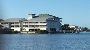 A waterfront hotel with multiple balconies, a green-roofed tower, and a dock extending into the water. - Waterfront Condo with an amazing view - Pet Friendly (Indian Shores)