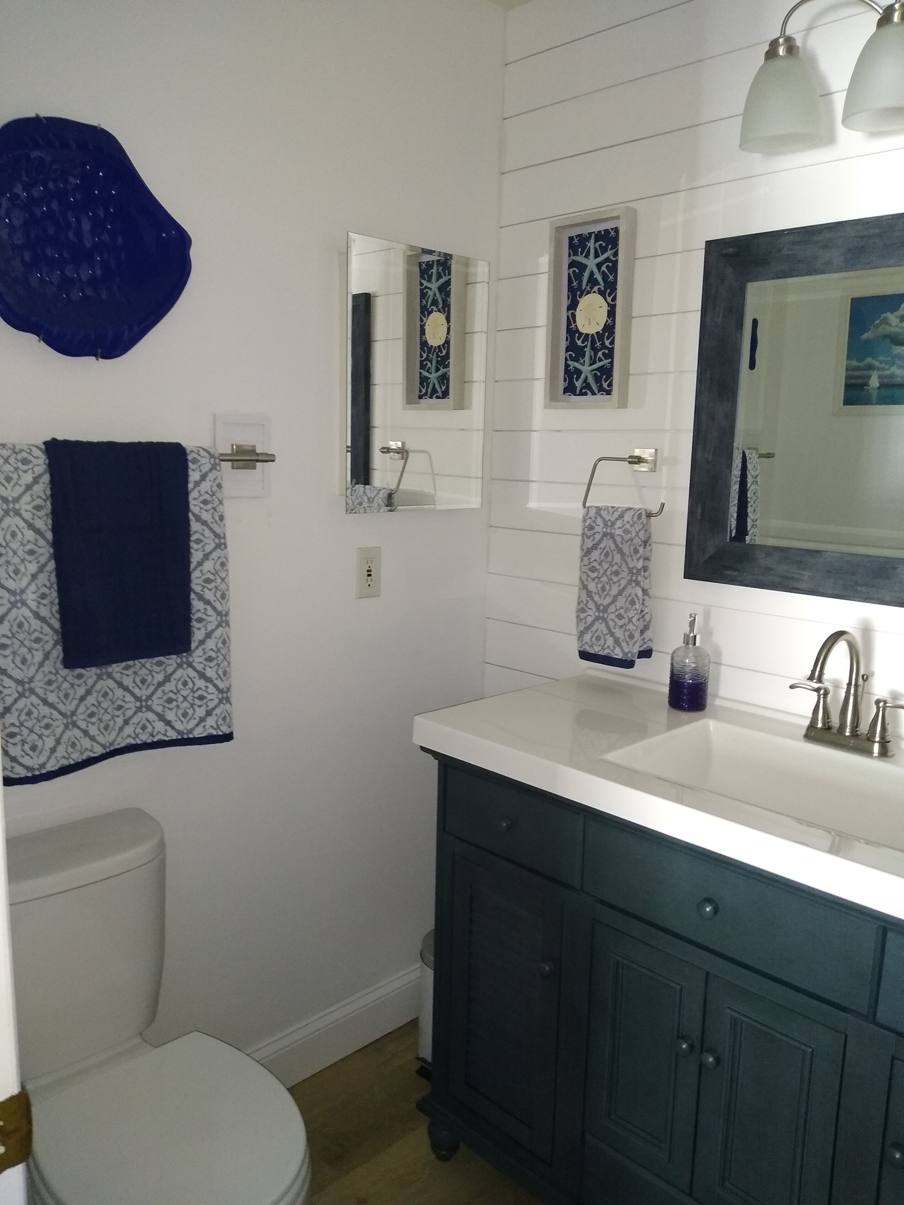 Un baño con un lavamanos blanco, armarios oscuros, un inodoro y espejos decorativos.