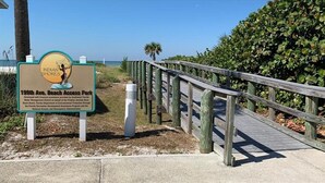 A wooden boardwalk leading to a beach area with a sign indicating 'Indian Shores' and '199th Ave. Beach Access Park'. - Waterfront Condo with an amazing view - Pet Friendly (Indian Shores)