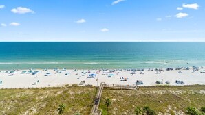 A beach with a wooden boardwalk leading to the shore, sandy beach, and clear blue sky. - Indigo 504E BeachFront!Bonus Den,Best View&Amenities HUGE Pool!HotTub Pickleball (Pensacola)