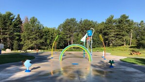 Un parque infantil con estructuras de juego coloridas, incluyendo un arcoíris y un tobogán con forma de pez.