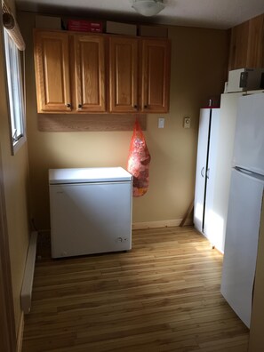 Una cocina compacta con armarios de madera, un refrigerador blanco y piso de madera.