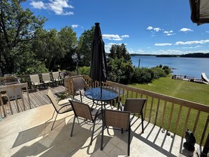 Une terrasse dotée de mobilier d’extérieur, d’une table et de chaises, avec vue sur un lac.