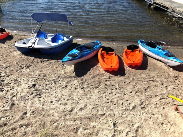 Une plage de sable avec des kayaks et un bateau.