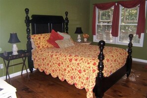 Una camera da letto con un letto, due comodini, una finestra con tende e una parete verde.