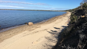 Une plage de sable avec un grand rocher et un ciel bleu dégagé.