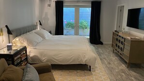 Une chambre moderne avec un grand lit, une télévision, une commode et une vue sur l’extérieur.