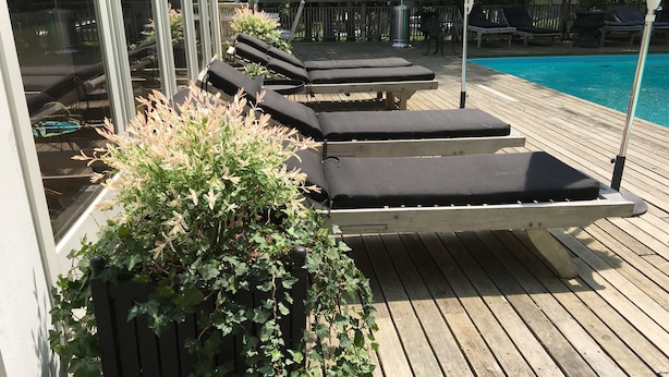 Une terrasse en bois avec des chaises longues et une piscine.