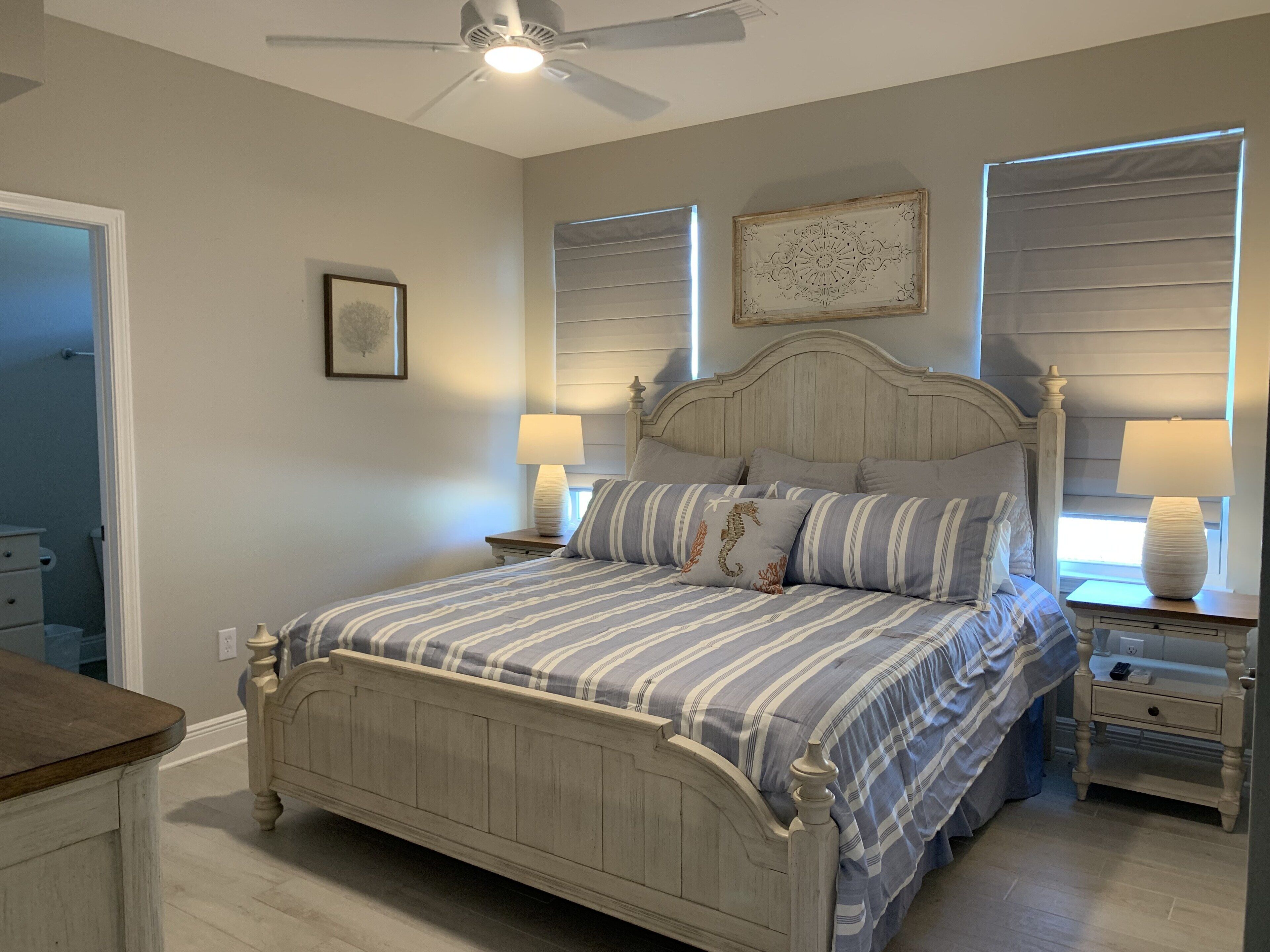 A bedroom with a bed, two bedside tables, a ceiling fan, and a window with blinds.