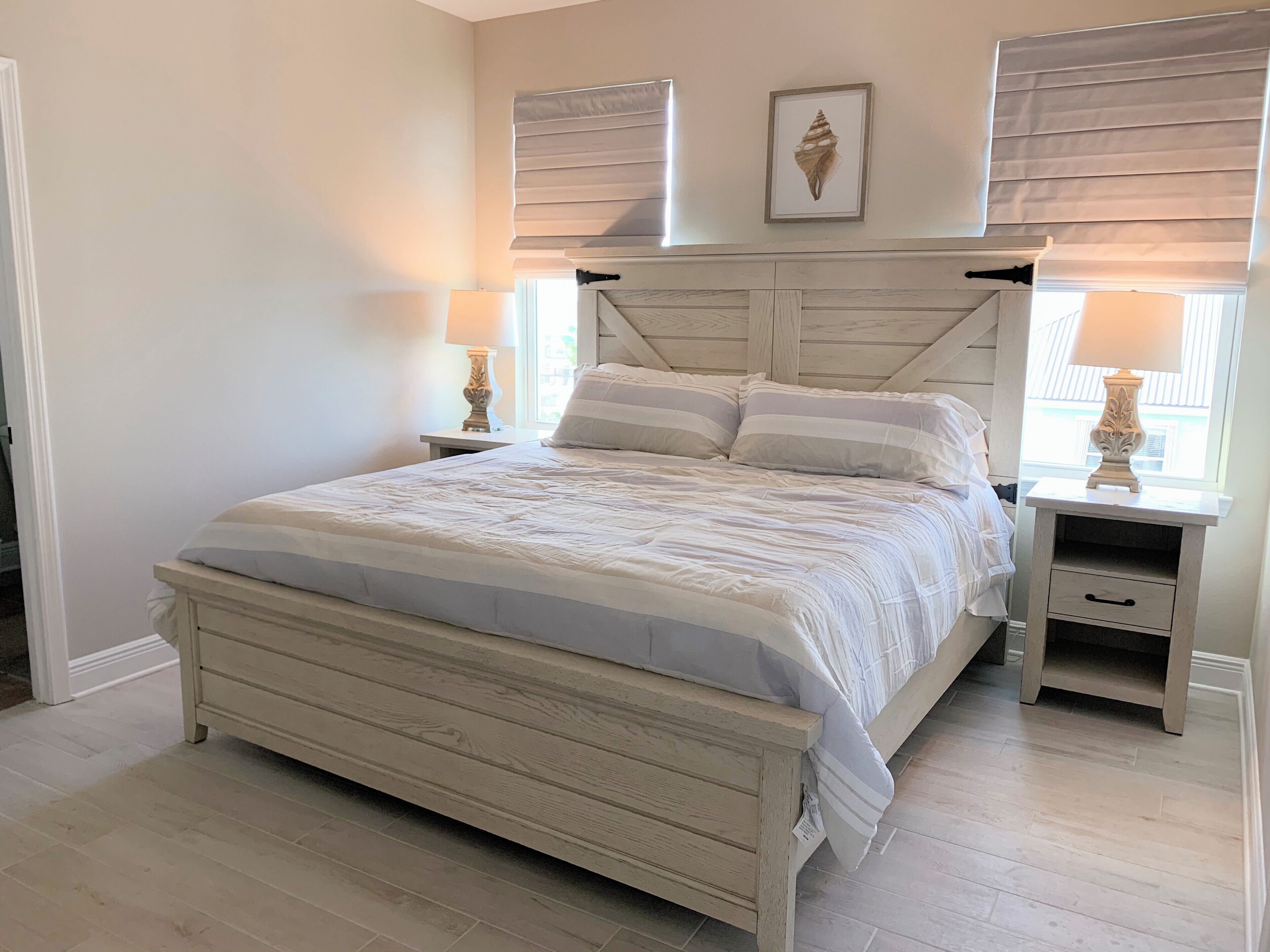 A bedroom with a bed, two bedside tables, a nightstand, and a window with blinds.