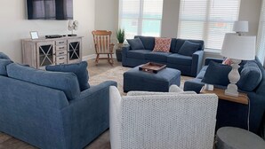 Ein Wohnzimmer mit zwei Sofas, einem Couchtisch, einem Beistelltisch, einem Fernseher und einem Deckenventilator.