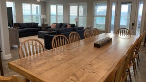 Ein geräumiges Wohnzimmer mit großem Holzesstisch, bequemen Sitzgelegenheiten und großen Fenstern mit Blick.