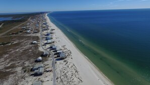 Ein Luftbild einer Küstenregion mit einem langen Sandstrand und einer Reihe von Gebäuden entlang des Ufers.